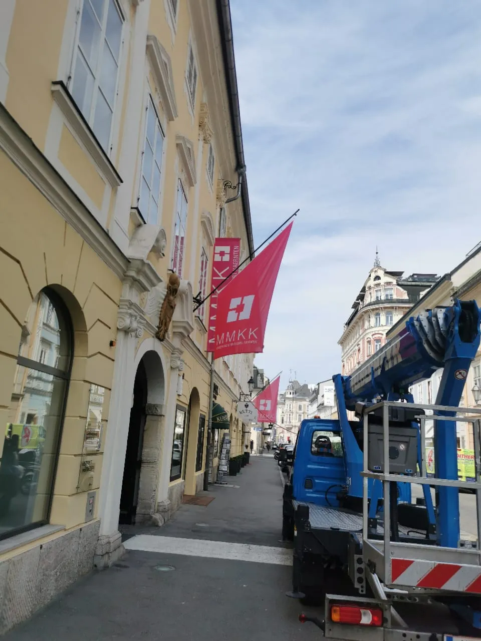 Pinke Auslegerfahnen an einer gelben Altstadtfassade, montiert vom Hubsteiger aus