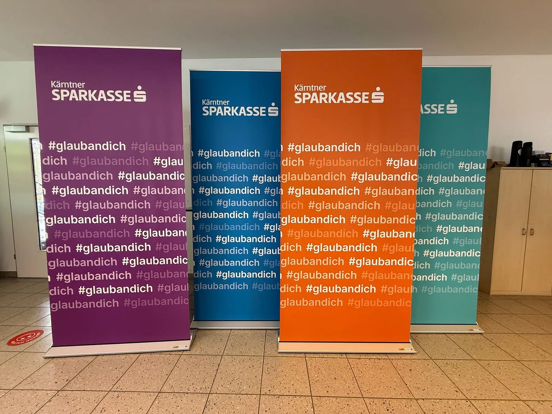 Vier Rollups der Kärntner Sparkasse mit dem Spruch #glaubandich