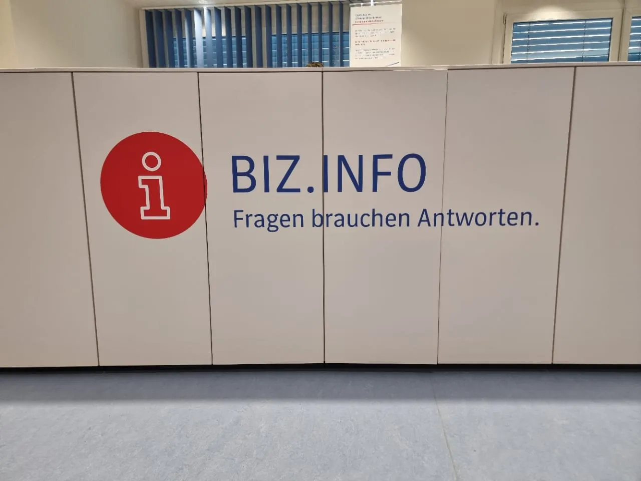 Feste Empfangstheke mit Beschriftung, ein rotes Zeichen mit Schriftzug und Leitspruch auf der Front