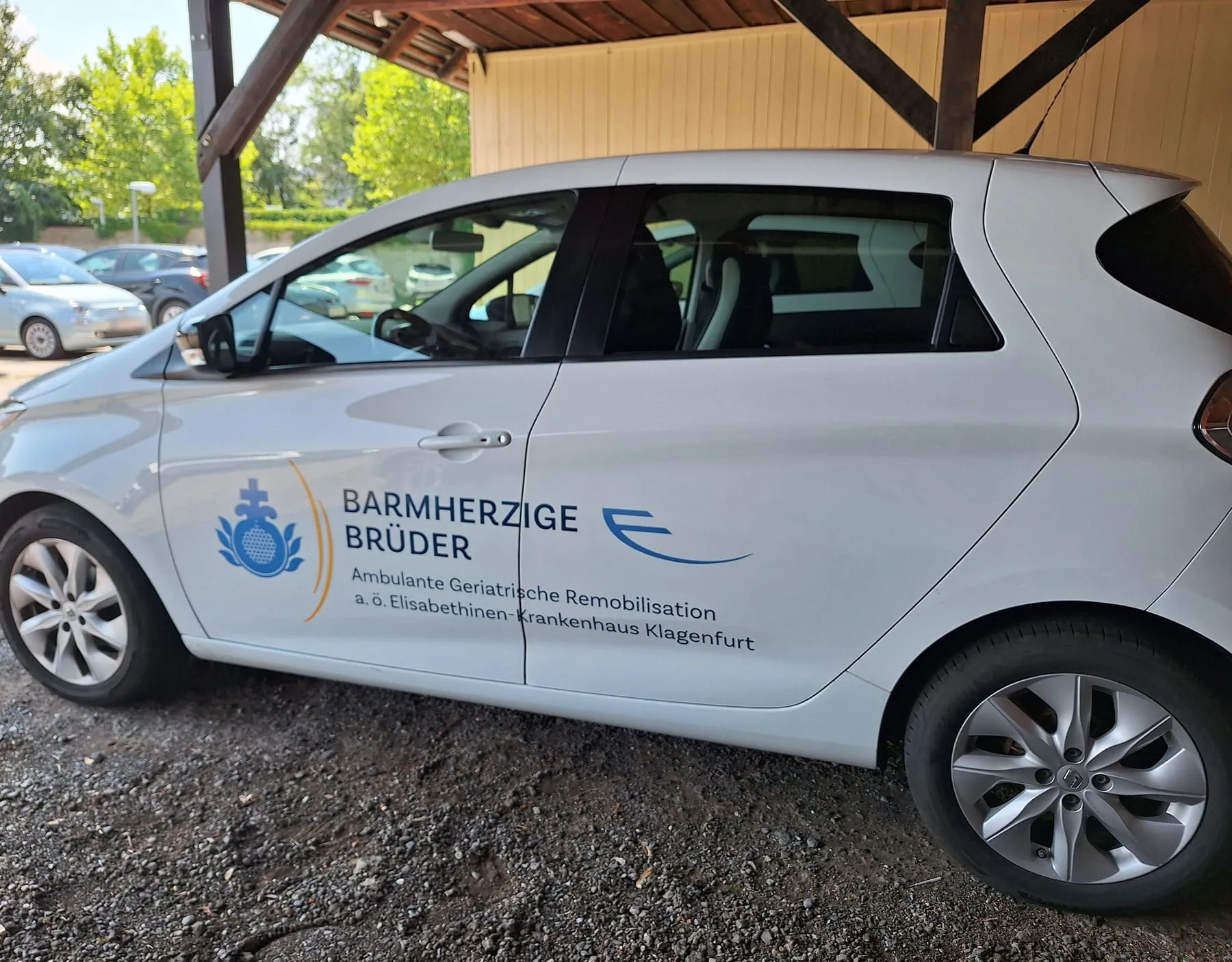 Renault Zoe mit Türbeschriftung der Ambulanten Geriatrischen Remobilisation im Carport