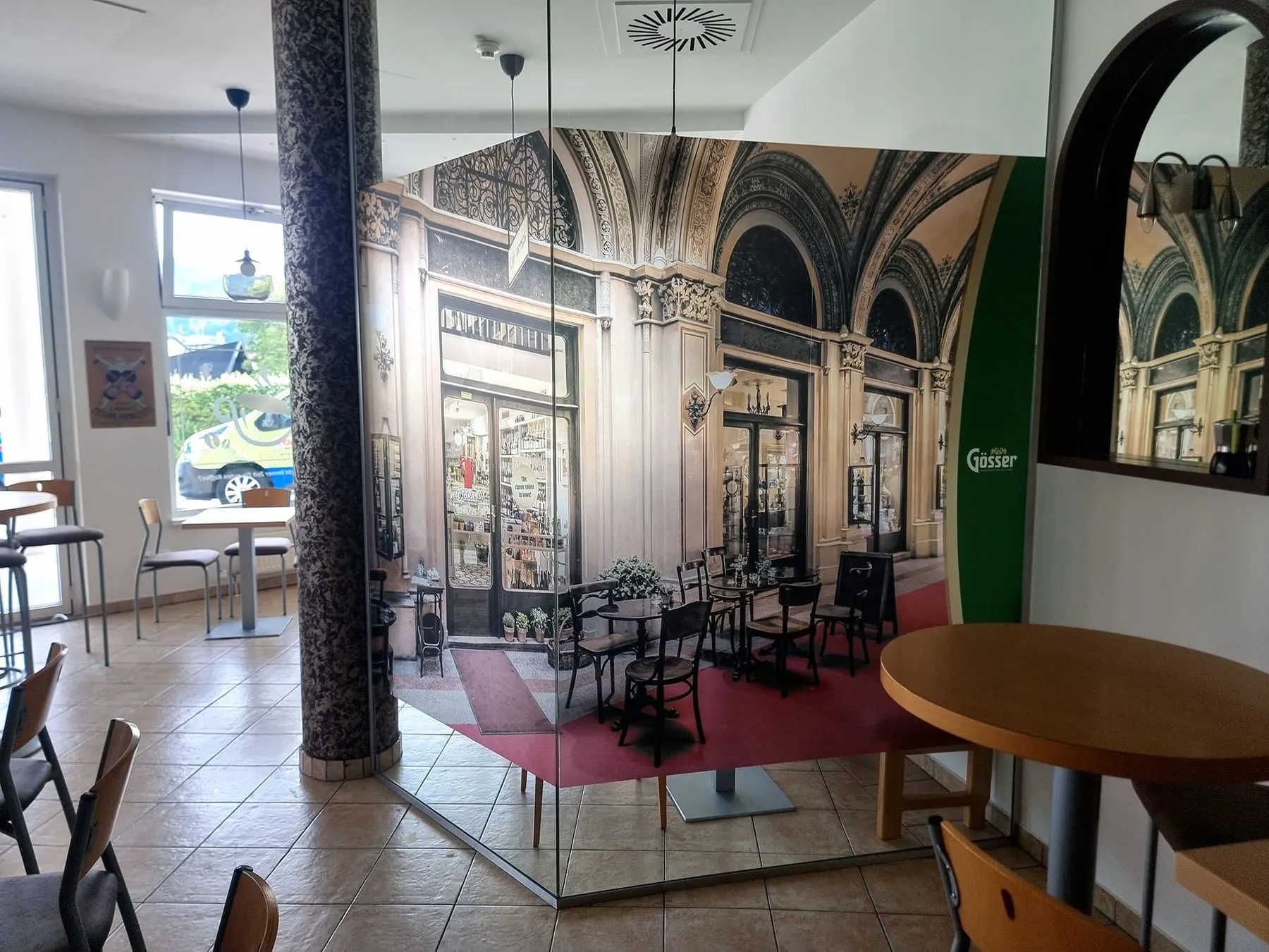 Glastrennwand in einem Lokal mit bedruckter Milchglasfolie, darauf das Fotomotiv eines Kaffeehauses