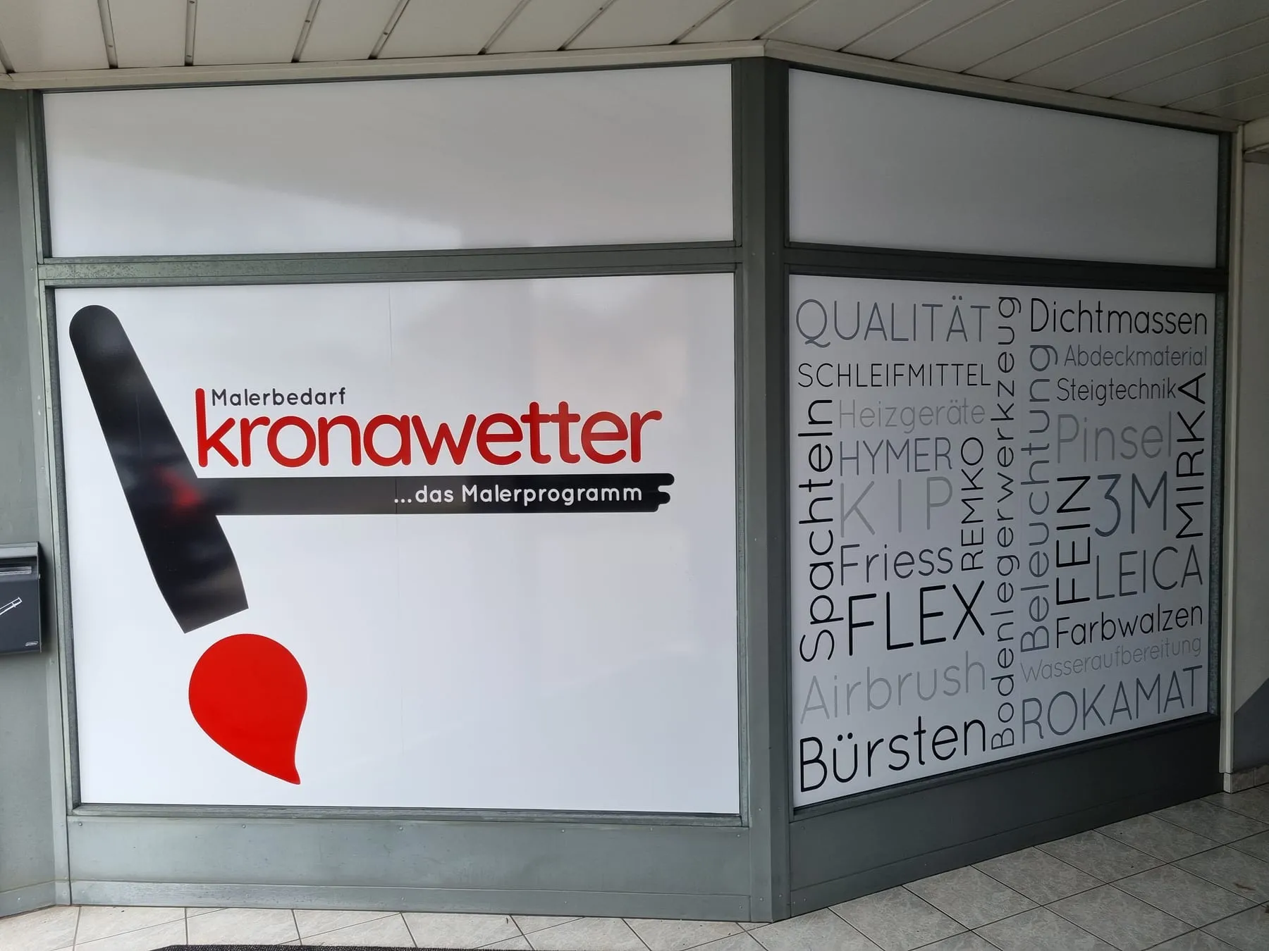 Schaufenster eines Malerbedarfs voll mit Folie beklebt, links das Logo und rechts eine Wortwolke