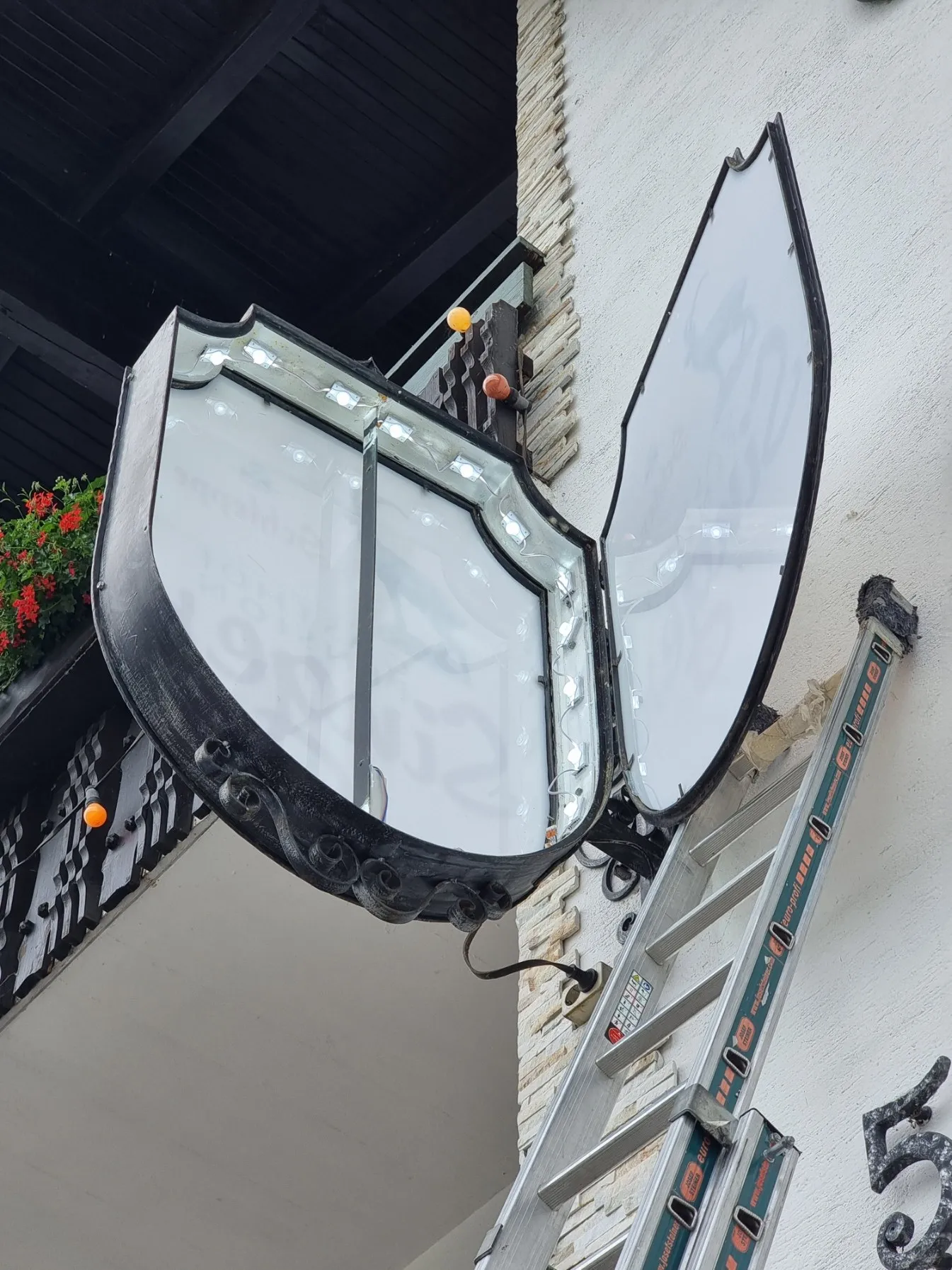 Wappenförmiger Ausleger des Gasthofs Singer, aufgeklappt, mit neuen LED-Modulen rundum am Rand