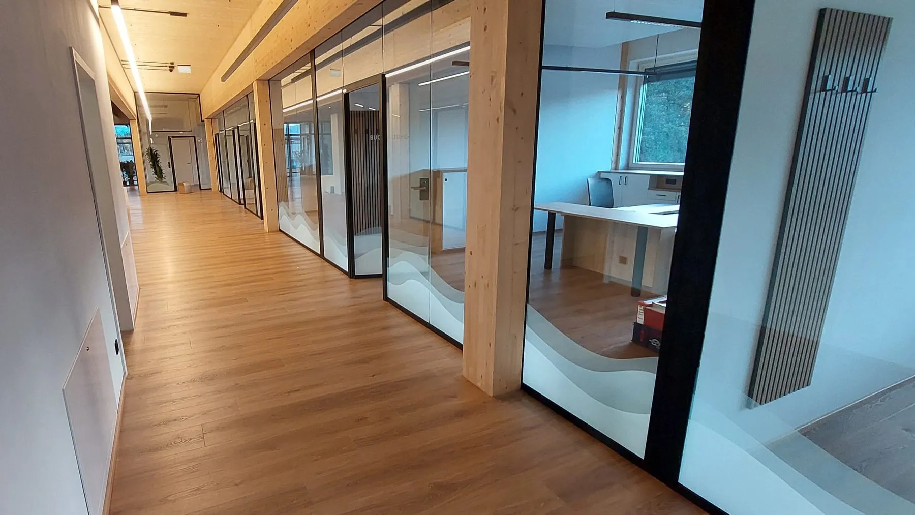 Bürogang mit Glaswänden, im unteren Drittel Milchglasfolie mit Wellenmotiv
