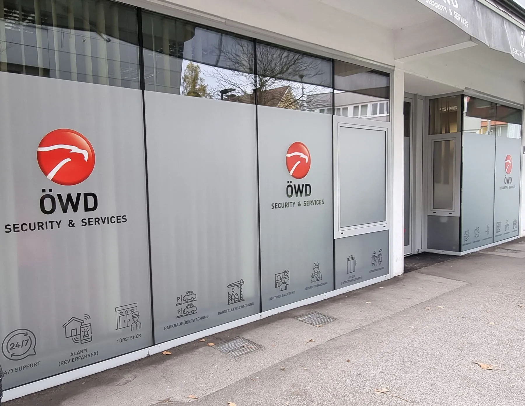 Schaufensterfront vom Boden bis über Kopfhöhe vollflächig mit Milchglasfolie, darauf Logo und Zeichen
