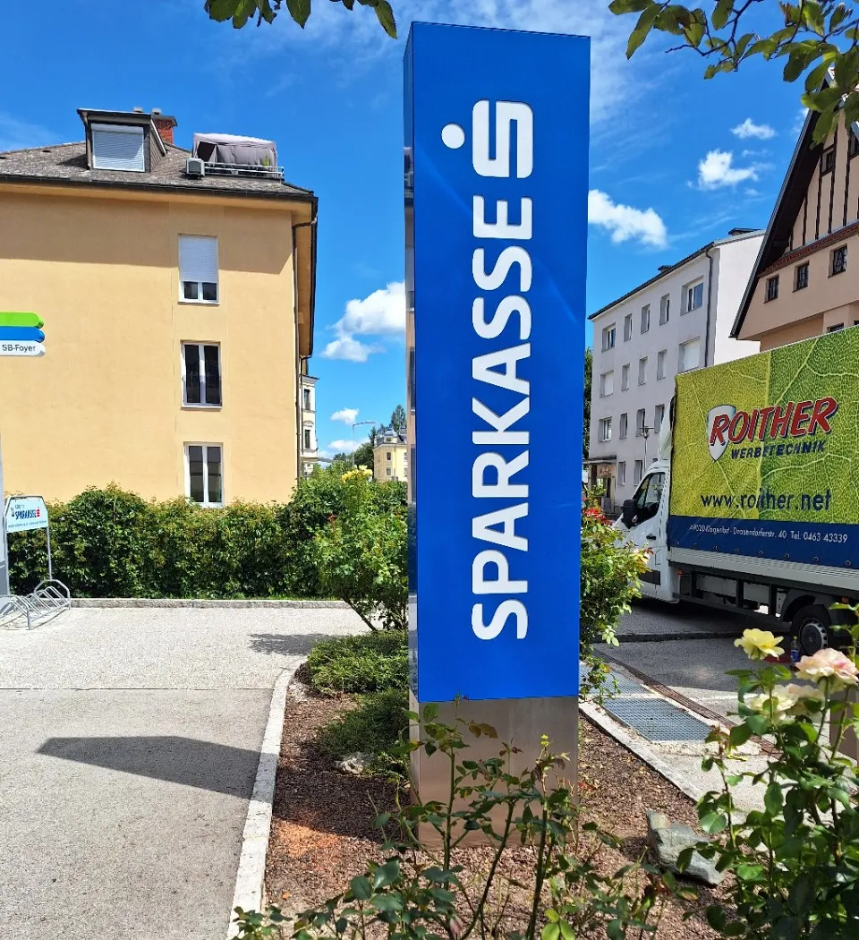 Blauer SPARKASSE-Pylon mit Edelstahlsockel, dahinter unser LKW