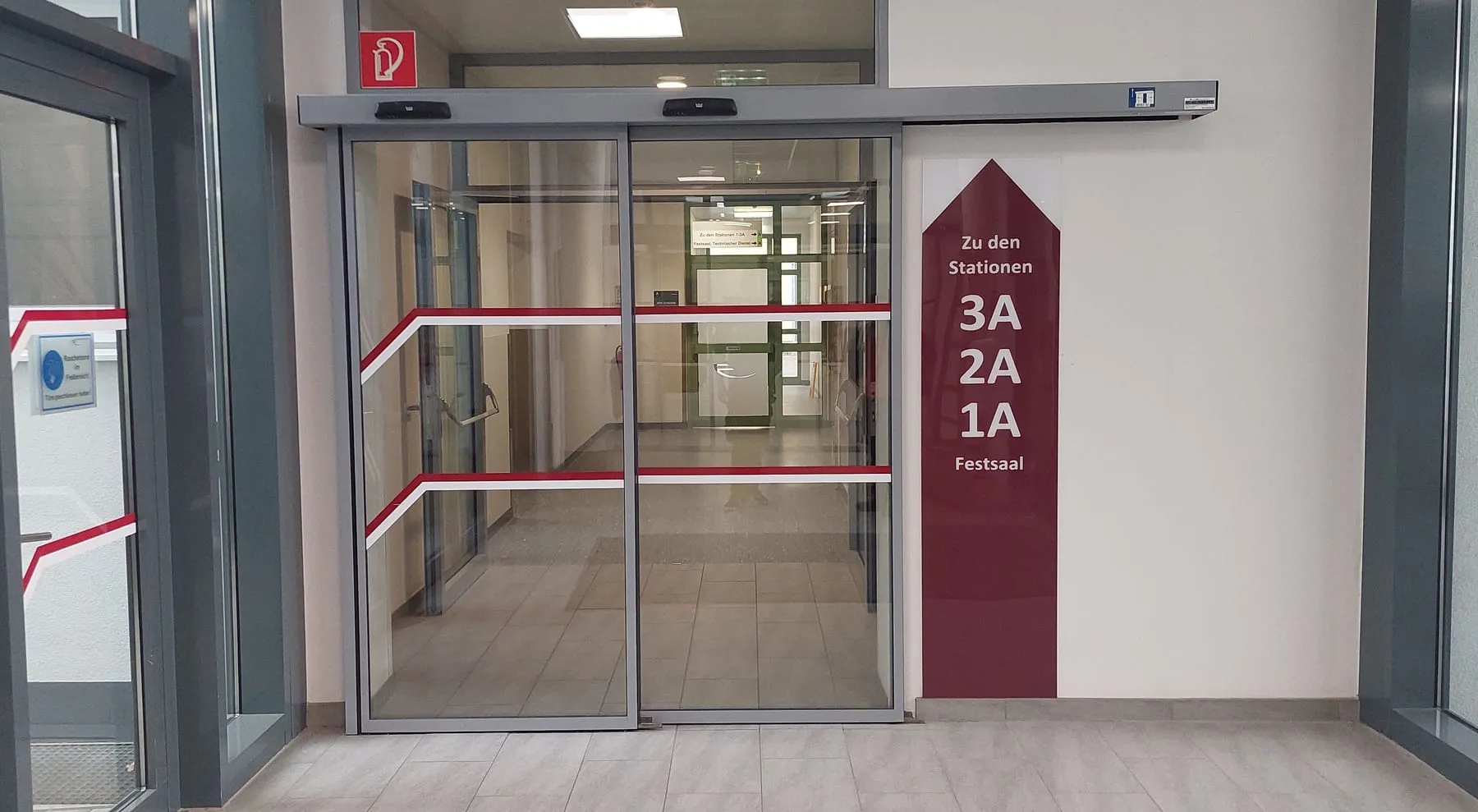 Wegweiser zu den Stationen und Glasmarkierung an der Schiebetür im Elisabethinen-Krankenhaus Klagenfurt